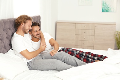 Happy gay couple on bed at home