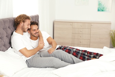 Photo of Happy gay couple on bed at home