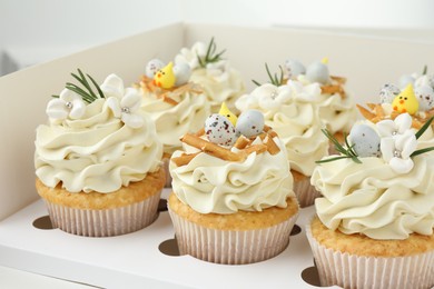 Photo of Tasty Easter cupcakes with vanilla cream in box, closeup