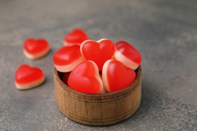 Bowl and delicious heart shaped jelly candies on brown table, closeup