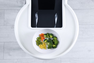 High chair with healthy baby food served on white tray indoors, top view