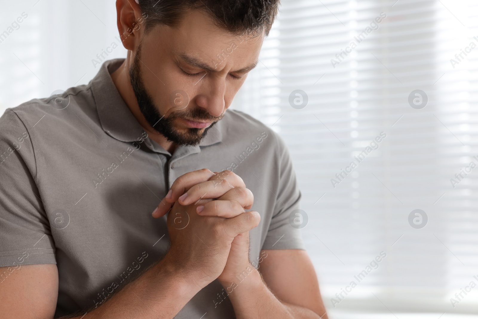 Photo of Religious man praying indoors. Space for text