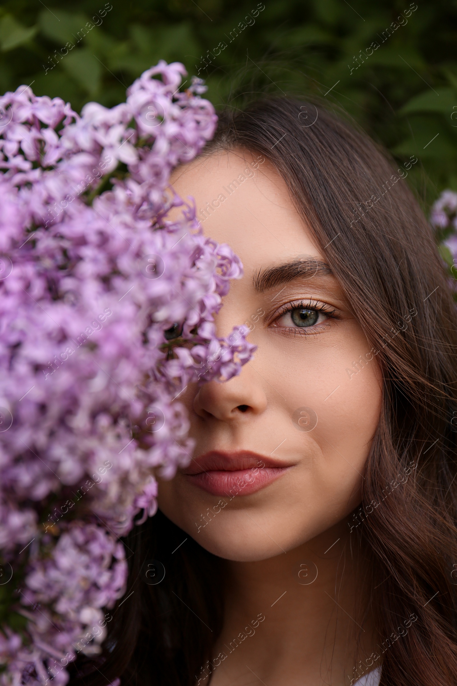 Photo of Attractive young woman near blooming lilac bush outdoors, closeup