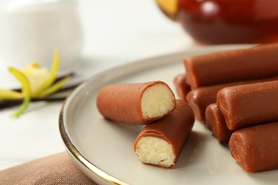 Glazed curd cheese bars, vanilla pods and flower on table, closeup