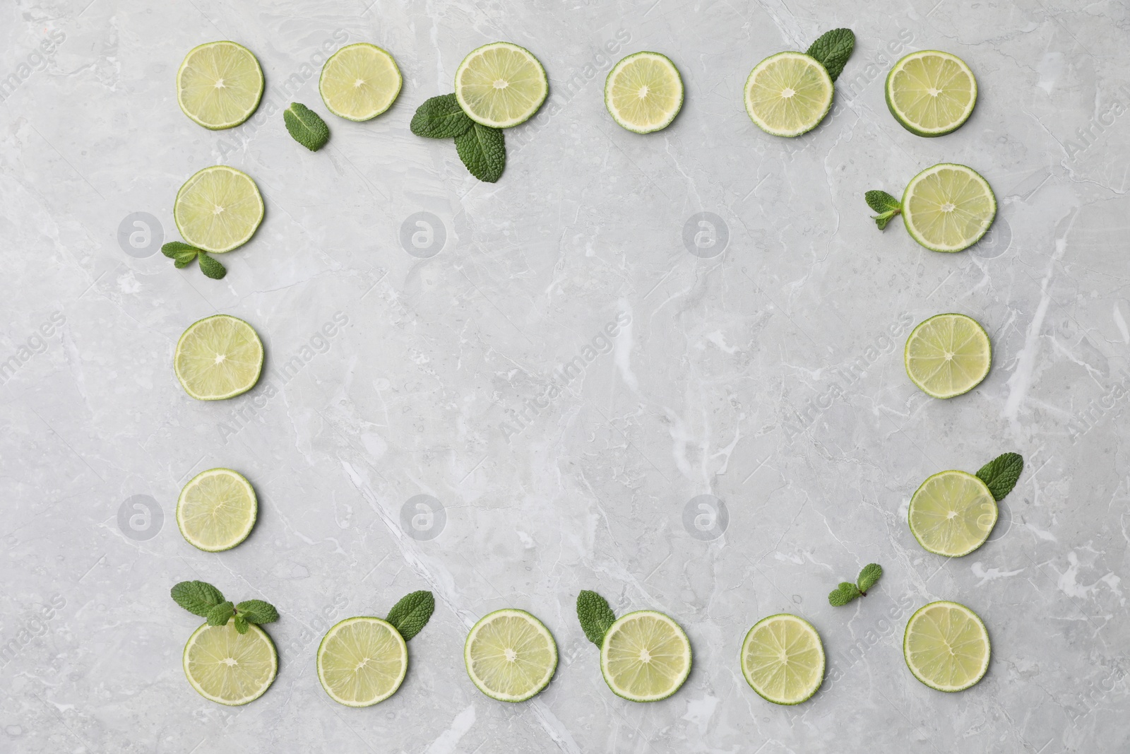 Photo of Flat lay composition with slices of fresh juicy limes on marble table. Space for text