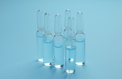 Many medical ampoules with solution for injection on light blue background