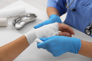 Photo of Doctor bandaging patient's burned hand at table, closeup