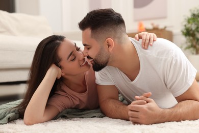 Photo of Affectionate young couple spending time together on soft carpet at home