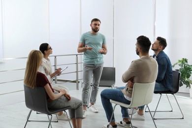 Photo of Psychotherapist working with group of drug addicted people at therapy session indoors