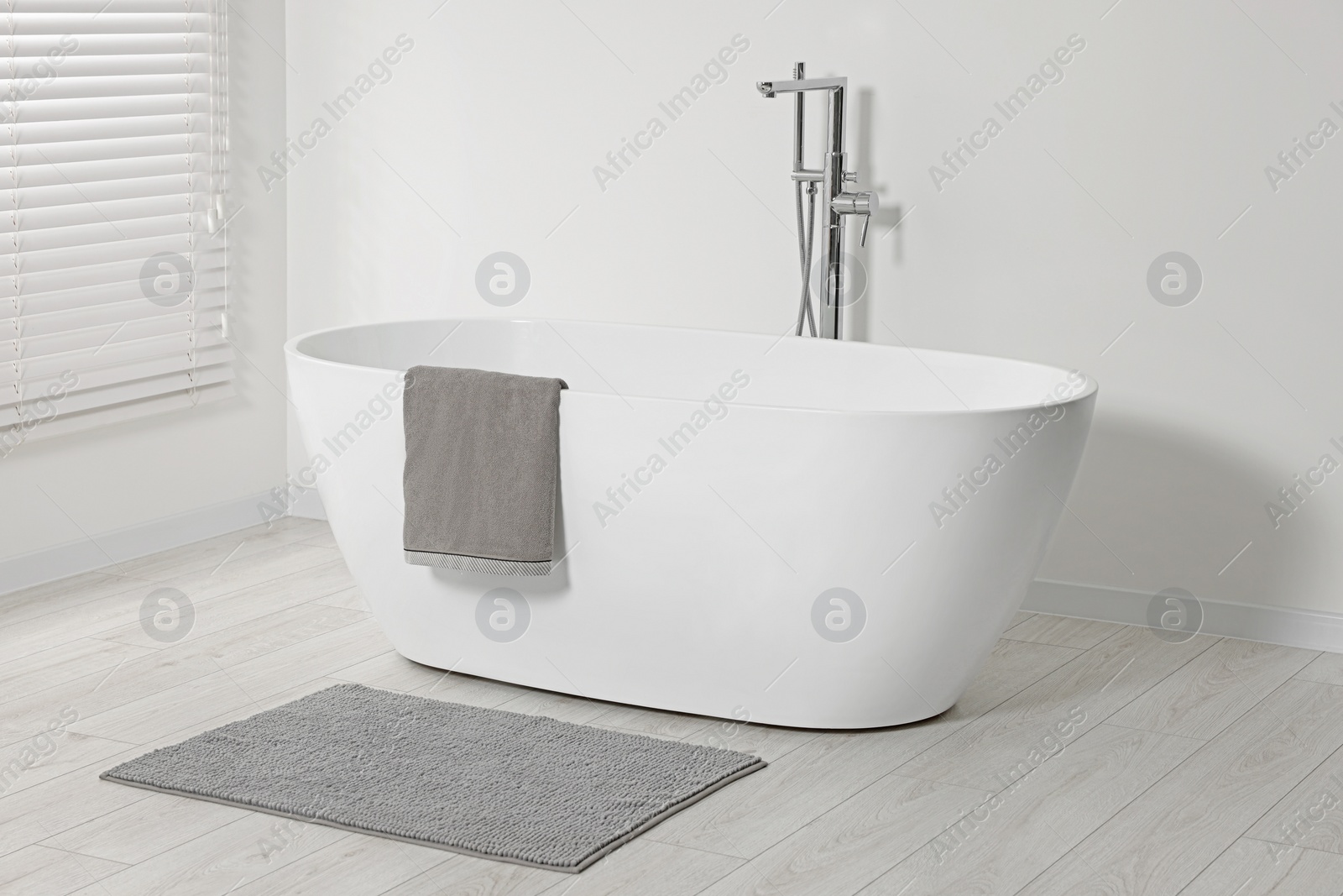 Photo of Stylish bathroom interior with ceramic tub and terry towel