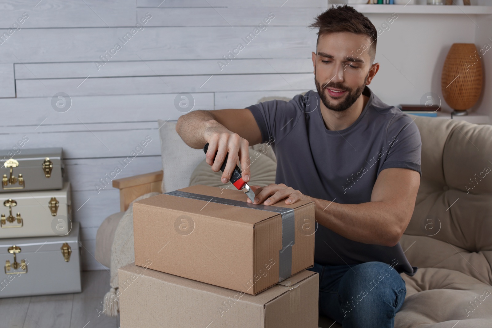 Photo of Man using utility knife to open parcel at home