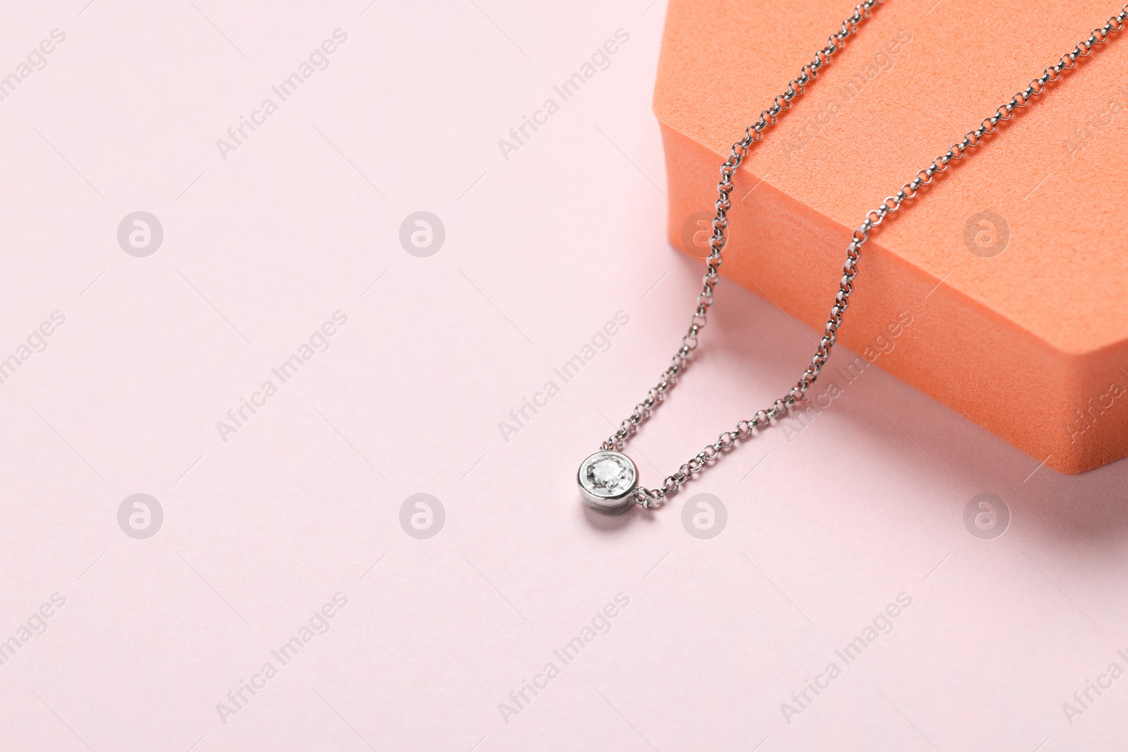 Photo of Beautiful necklace with gemstone on light background, space for text. Luxury jewelry