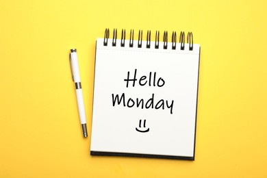 Image of Start your week with good mood. Open notebook with text Hello Monday and pen on yellow background, flat lay