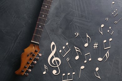 Guitar neck, music notes and symbols on grey background, top view