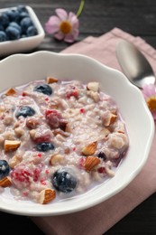 Tasty oatmeal porridge with toppings on wooden table, closeup