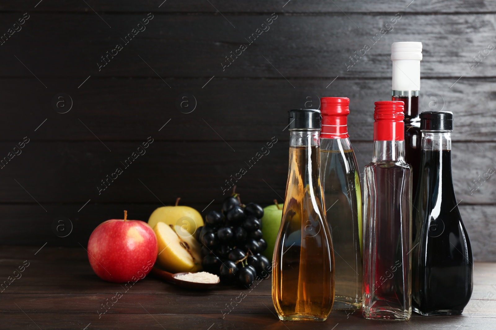 Photo of Composition with different kinds of vinegar and ingredients on wooden table. Space for text