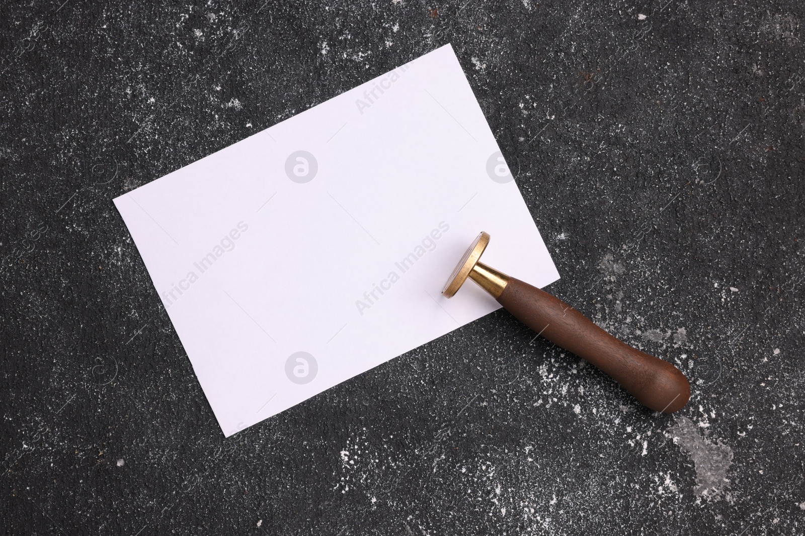 Photo of One stamp tool and sheet of paper on dark textured background, top view. Space for text