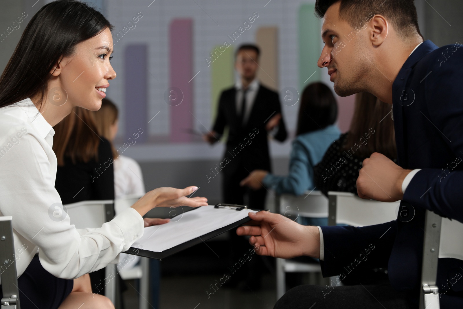 Photo of Young people having business training in conference room with projection screen