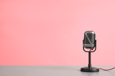 Photo of Vintage microphone on table against pink background, space for text