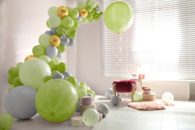 Image of Balloon garland near white wall in room. Festive decor