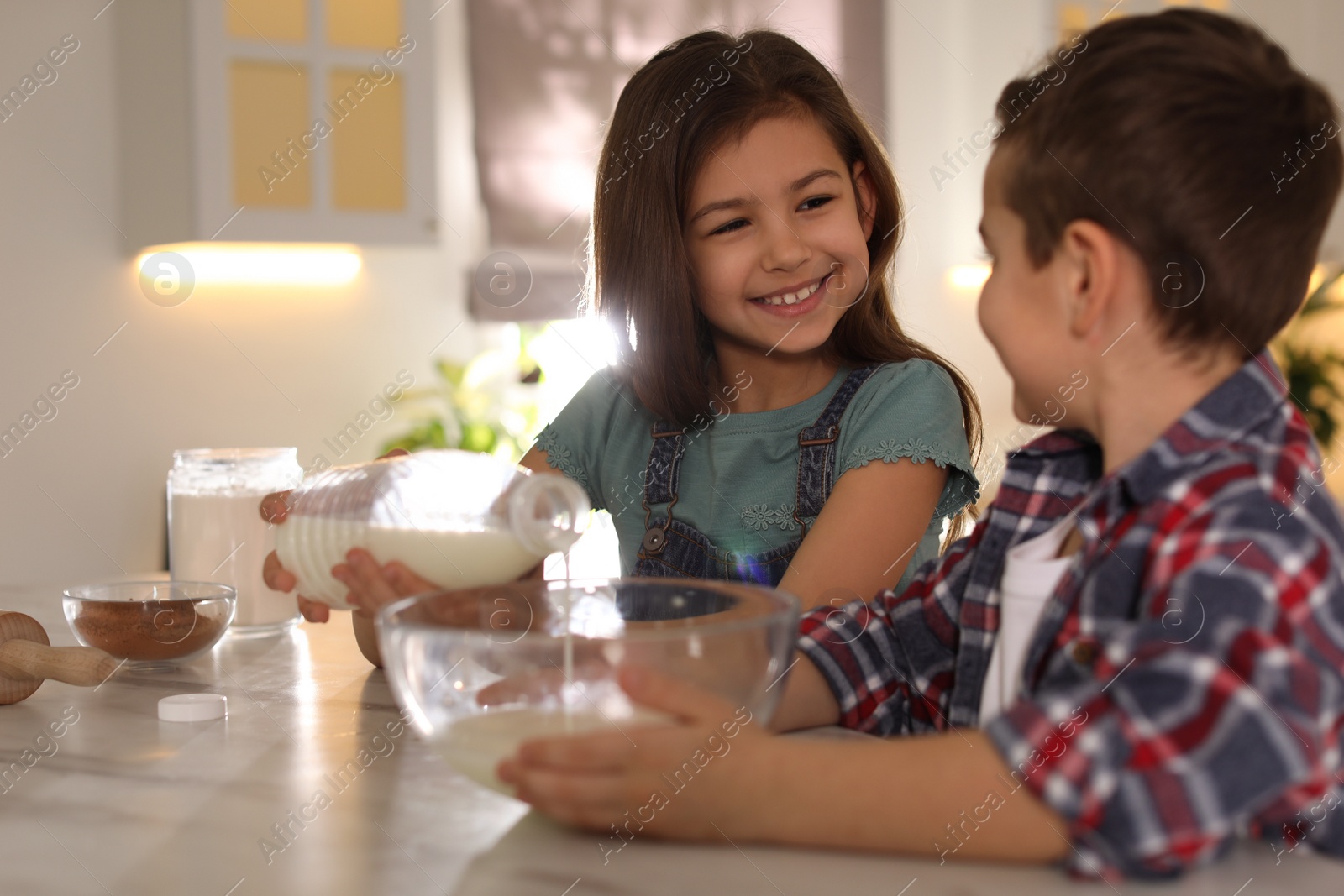 Photo of Cute little children cooking dough in kitchen at home