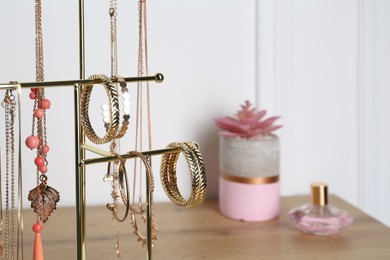 Photo of Interior element. Holder with set of luxurious jewelry on wooden dressing table, closeup