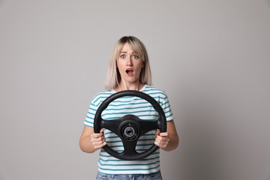 Photo of Emotional woman with steering wheel on grey background