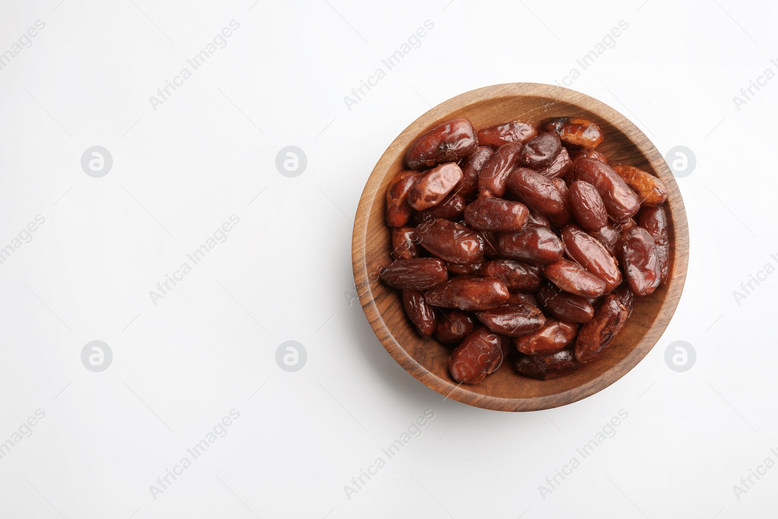 Photo of Bowl with sweet dried date fruits on white background, top view. Space for text