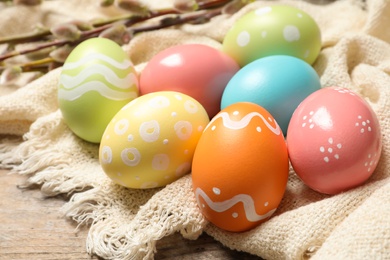 Photo of Colorful painted Easter eggs and cloth on table, closeup