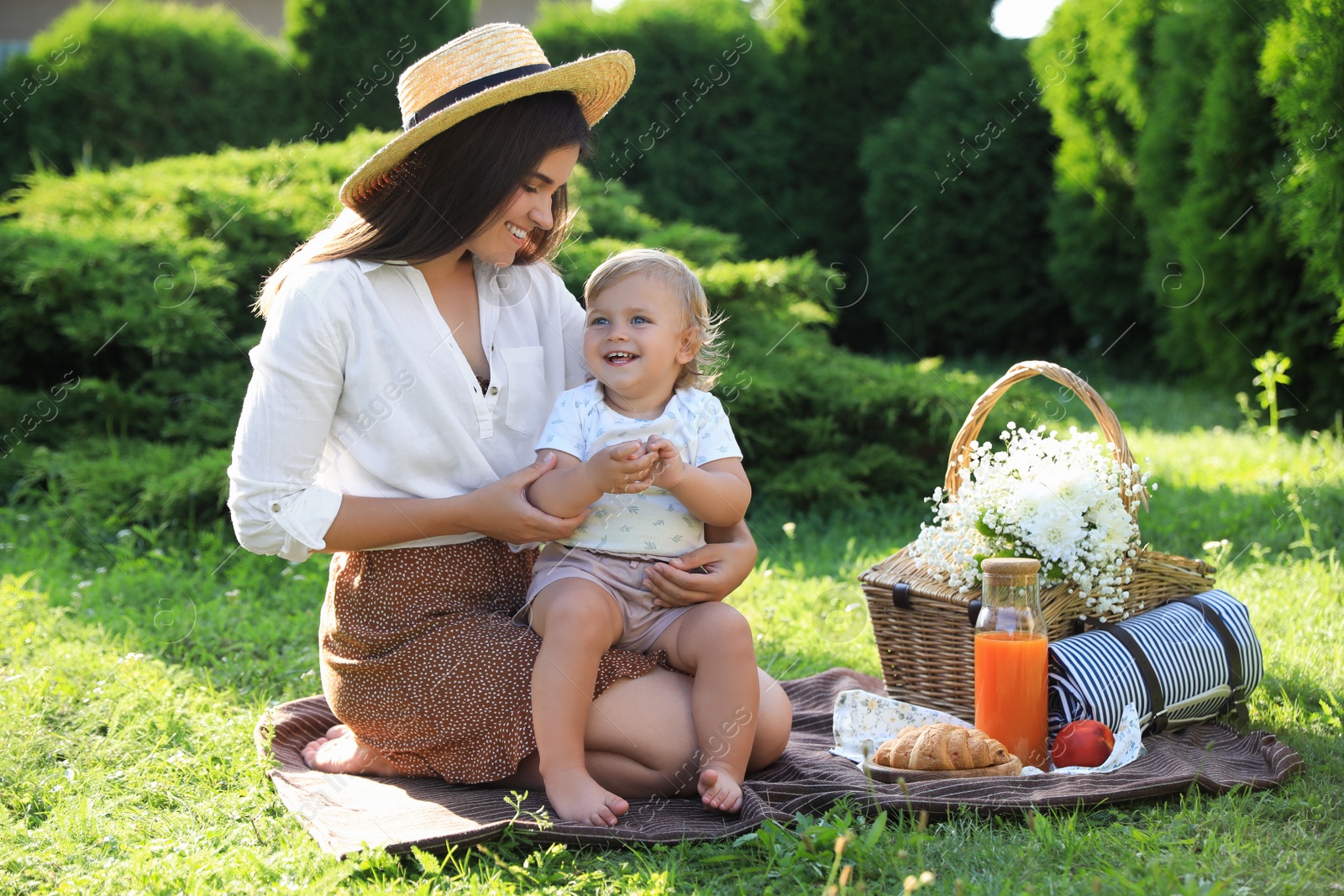 Photo of Mother with her baby daughter having picnic in garden on sunny day