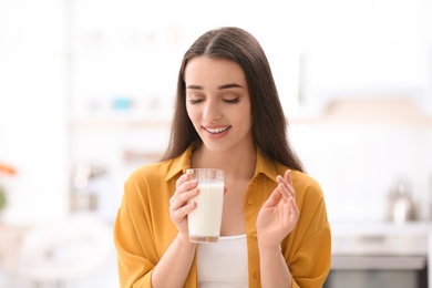 Photo of Beautiful young woman drinking milk at home