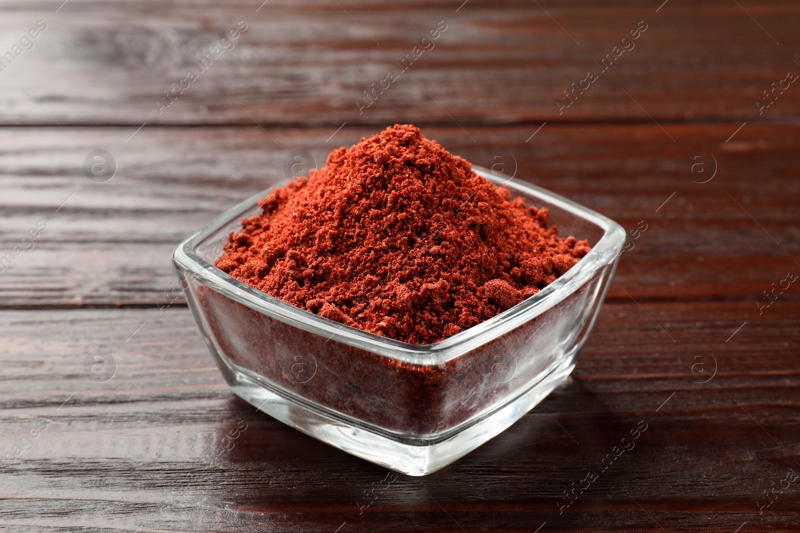 Photo of Dried cranberry powder in glass bowl on wooden table, closeup