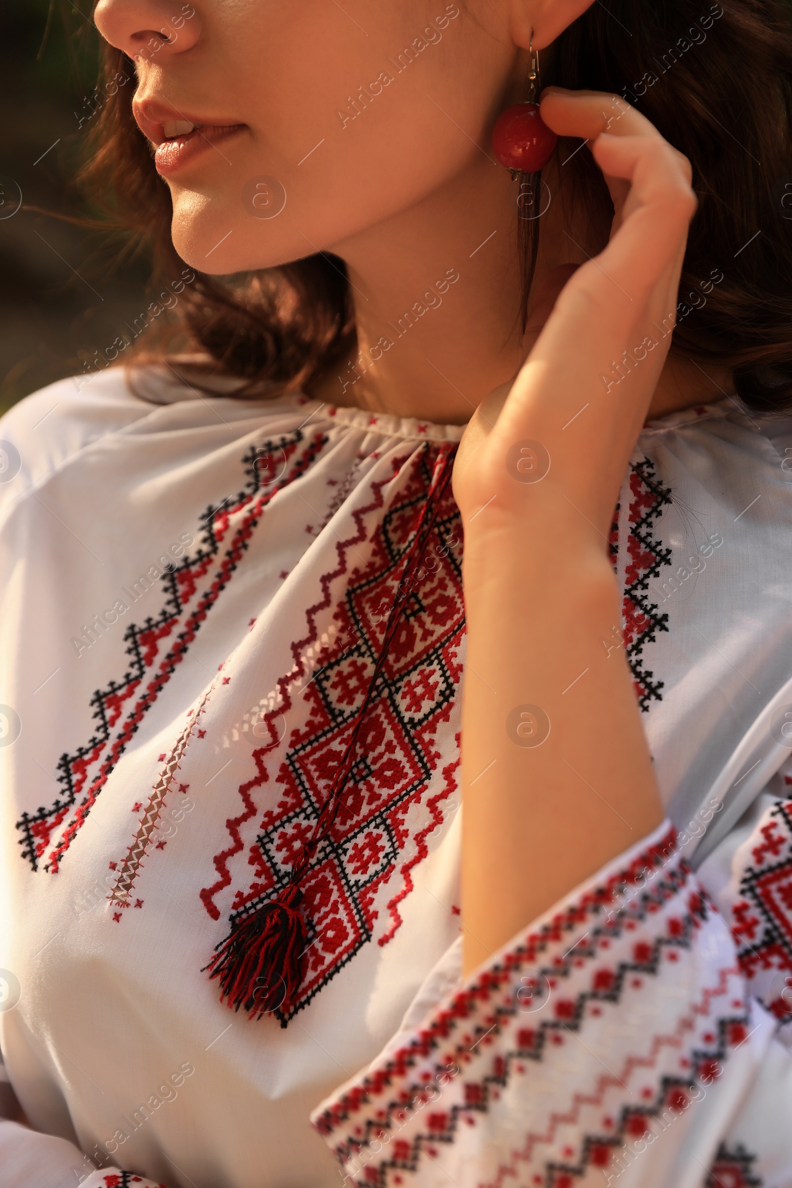 Photo of Woman in beautiful embroidered shirt outdoors, closeup. Ukrainian national clothes