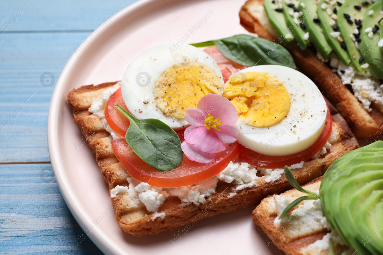 Photo of Delicious sandwich with cheese, egg and tomato on light blue wooden table, closeup