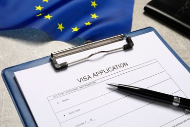 Photo of Visa application form, pen and flag of European Union on light grey table, closeup