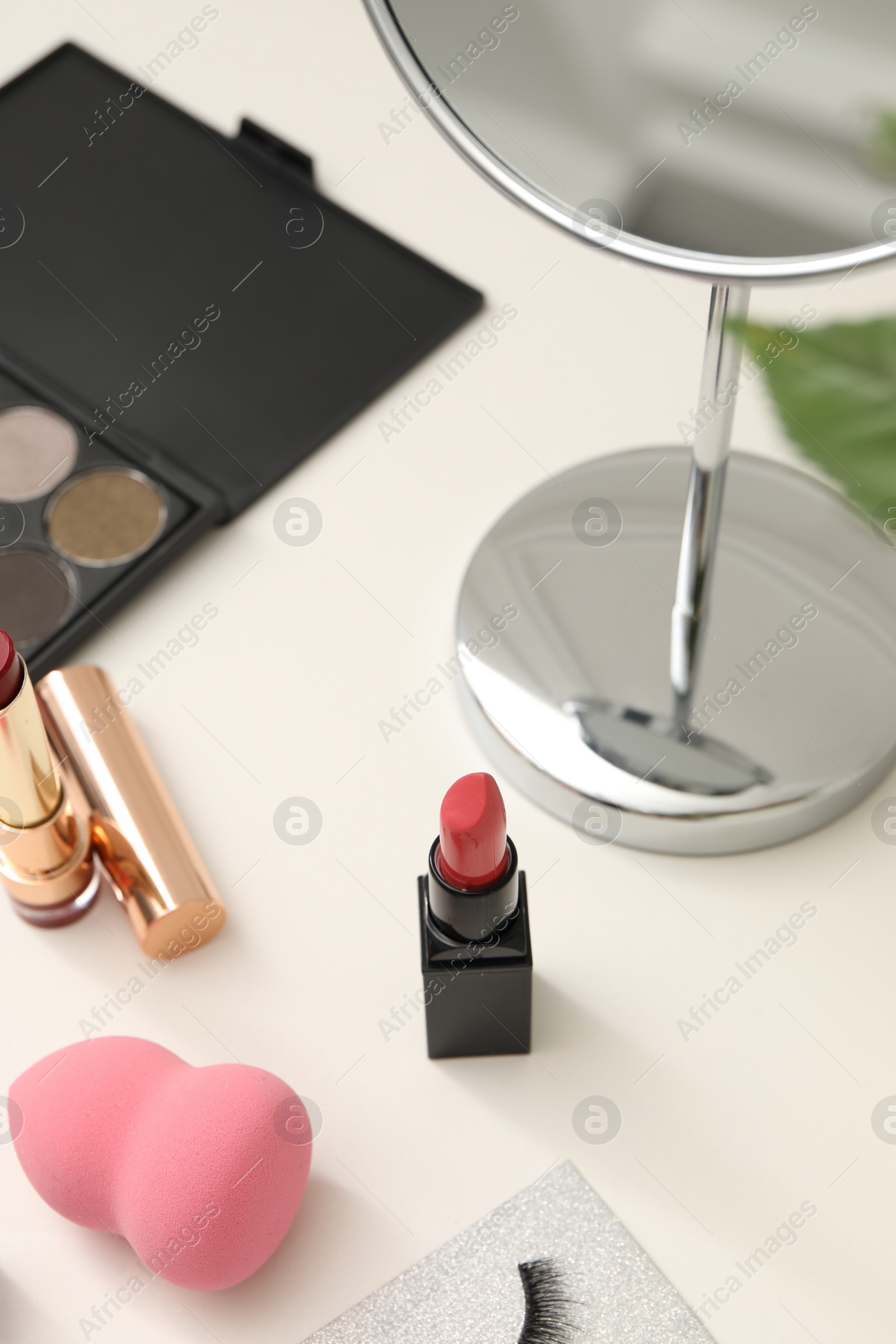 Photo of Mirror and cosmetic products on white dressing table, above view