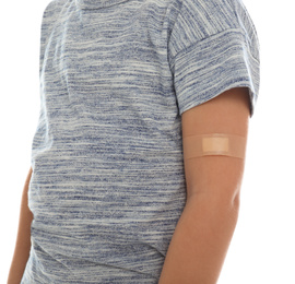 Photo of Little boy with sticking plaster on arm against white background, closeup