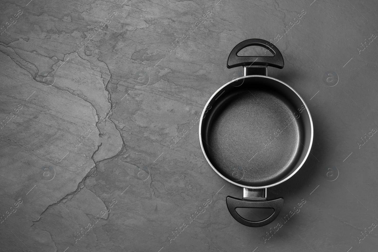 Photo of Empty pot on black table, top view. Space for text