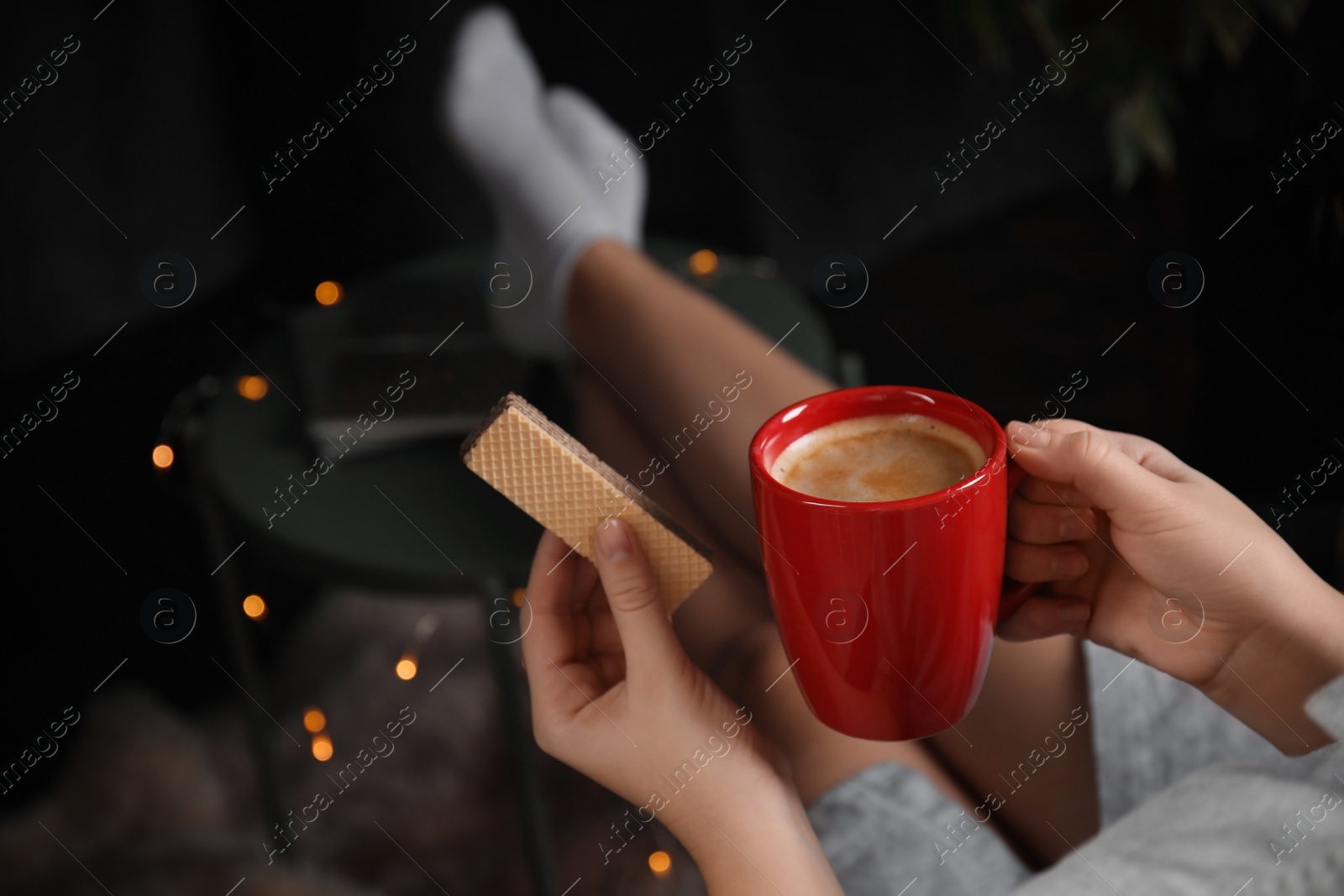 Photo of Woman with wafer and coffee on dark background, closeup. Early breakfast