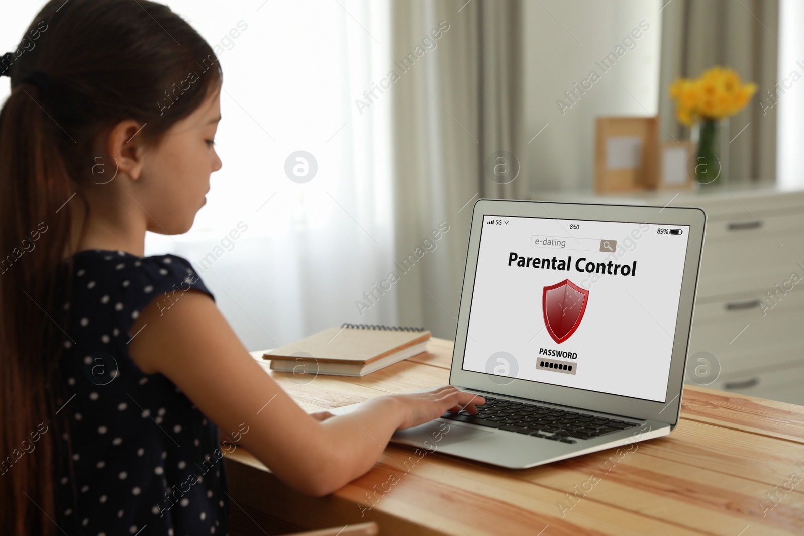 Photo of Child using laptop with installed parental control app at home. Cyber safety