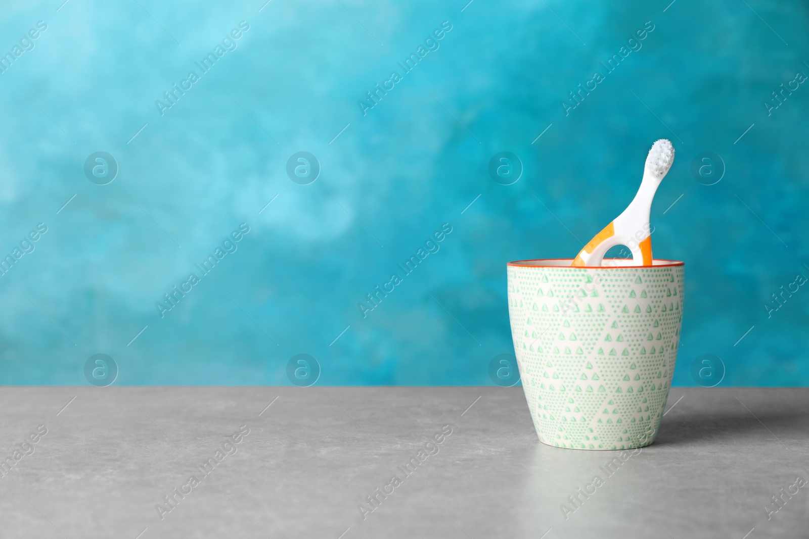 Photo of Baby toothbrush in holder on table against color background with space for text