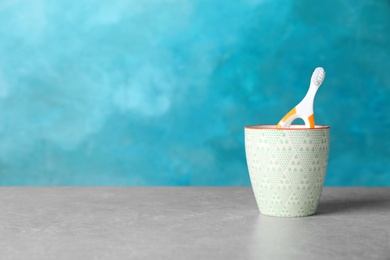 Baby toothbrush in holder on table against color background with space for text