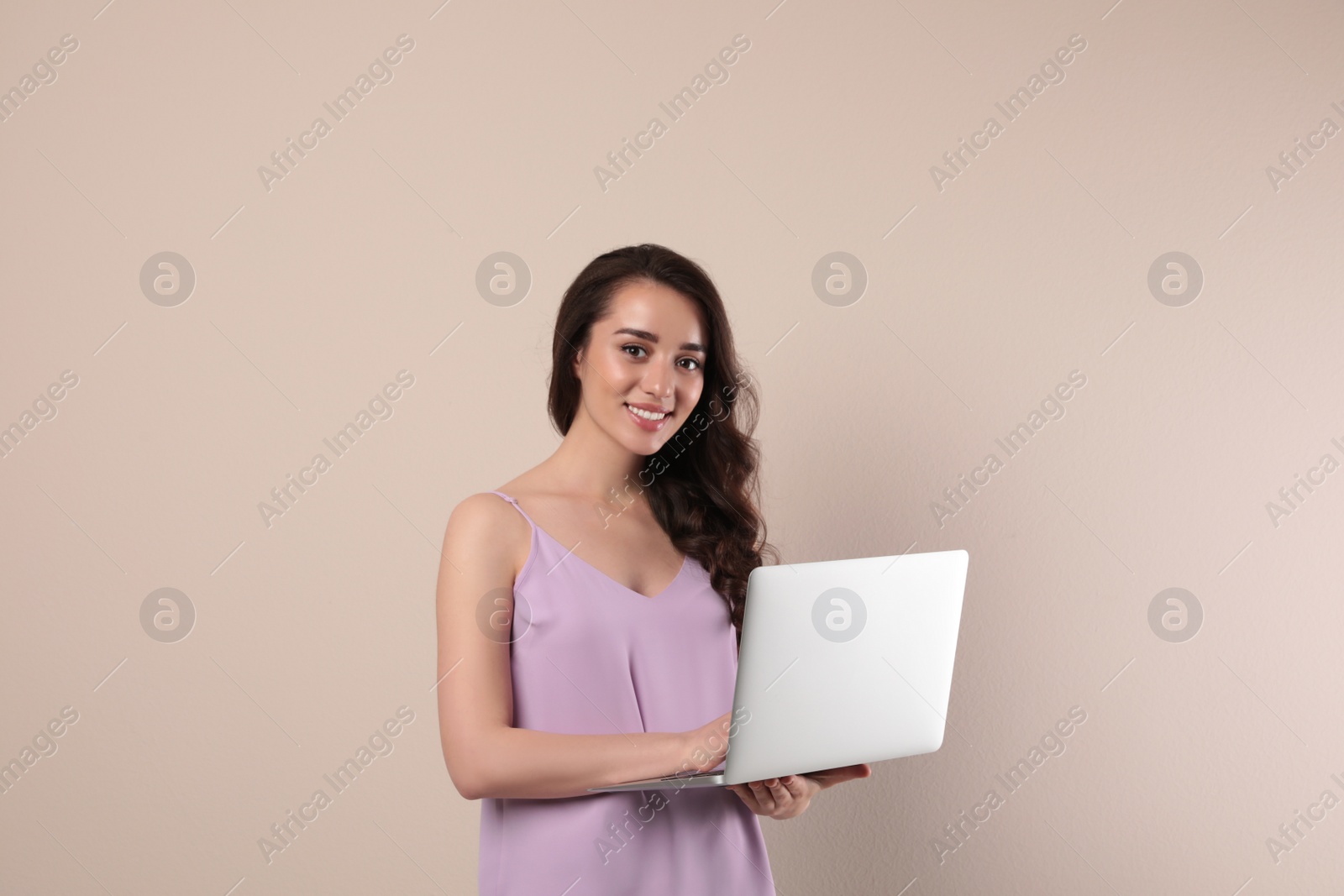 Photo of Young woman with laptop on beige background