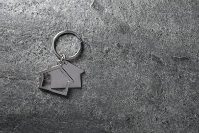 Photo of Metal keychain in shape of houses on grey textured table, top view. Space for text