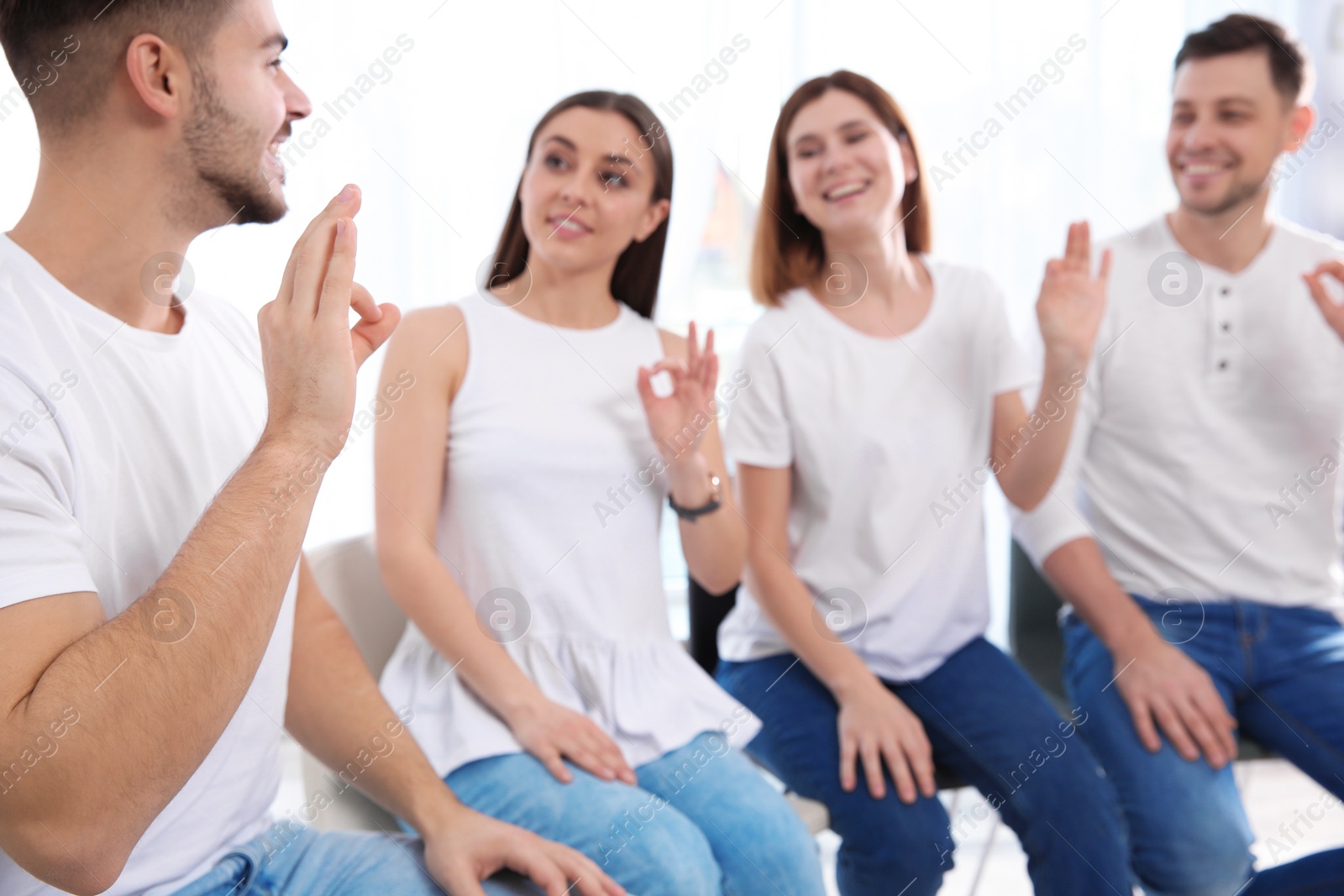 Photo of Group of young people learning sign language with teacher indoors