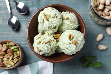 Photo of Delicious pistachio ice cream served on blue wooden table, flat lay