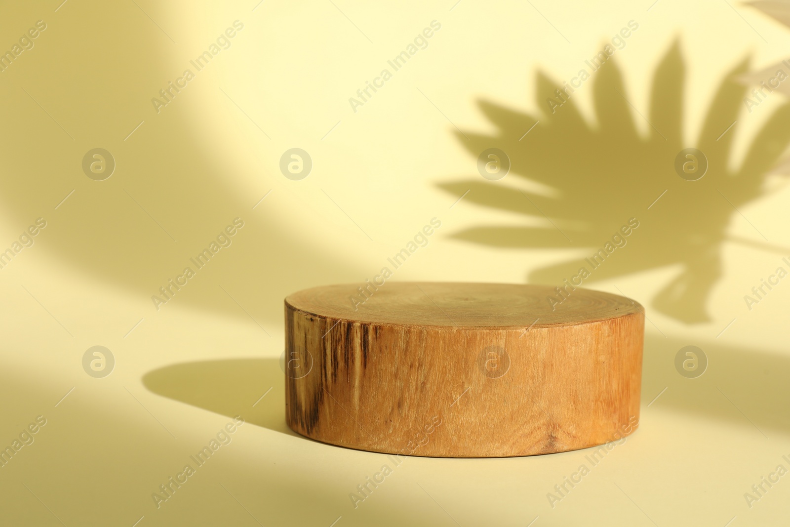 Photo of Presentation of product. Wooden podium on yellow background. Space for text