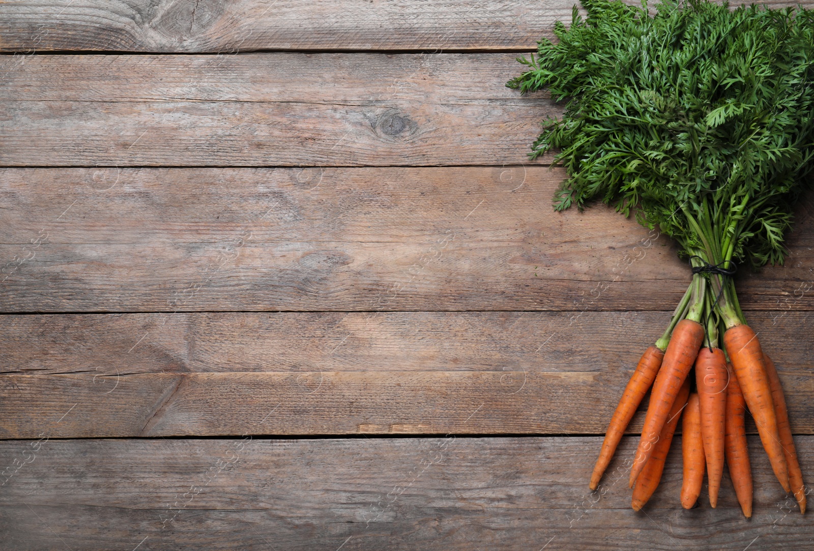 Photo of Ripe carrots on wooden table, top view. Space for text