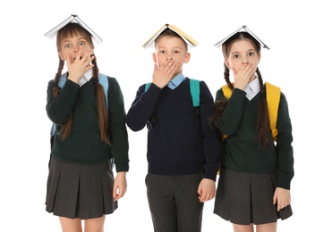 Photo of Portrait of funny children in school uniform with books on heads against white background