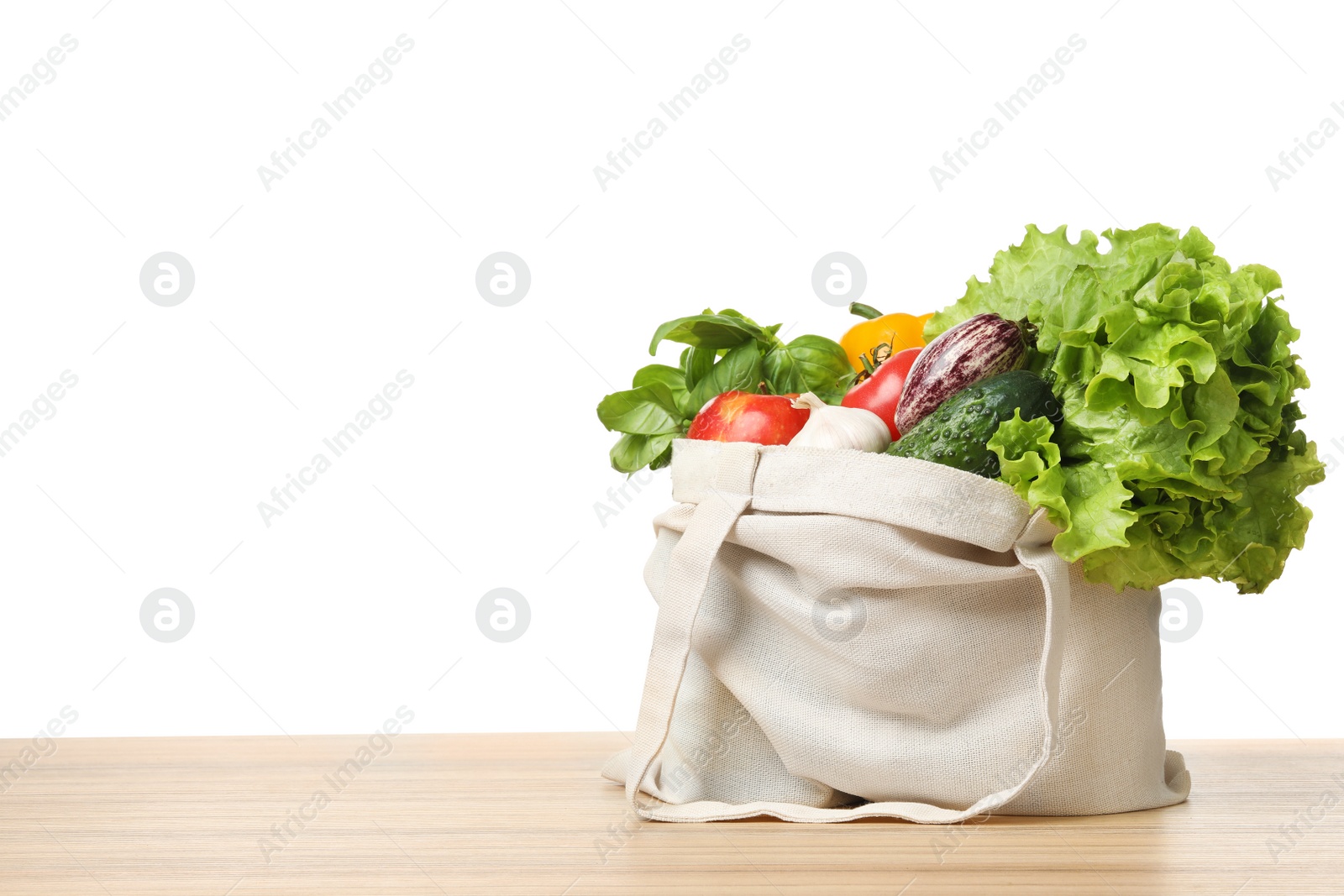 Photo of Cloth bag with vegetables on table against white background. Space for text